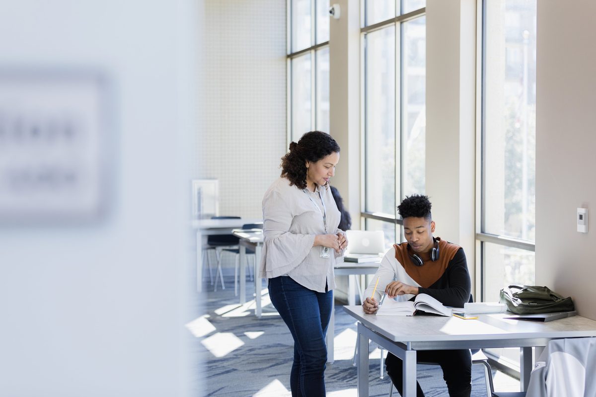 A tutor working one-on-one with a student at a desk in a bright modern learning environment — The Importance of Tutors in Modern Education